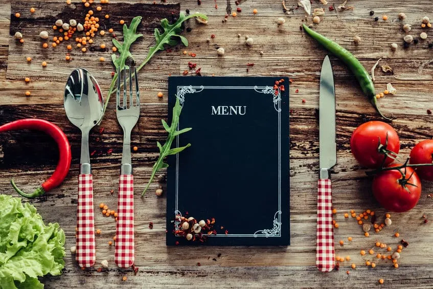 restaurant menu. top view of chalkboard menu laying on the rustic wooden desk with vegetables around