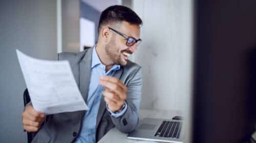 Homme souriant en costume tenant un document au bureau