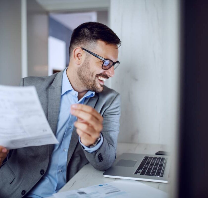 Homme souriant en costume tenant un document au bureau