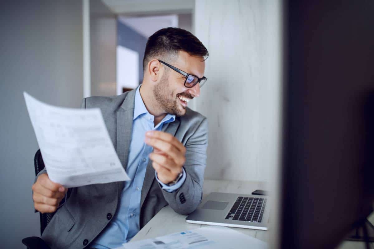 Homme souriant en costume tenant un document au bureau