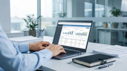 Un professionnel travaillant sur un ordinateur portable affichant un tableau de bord financier dans un bureau lumineux.